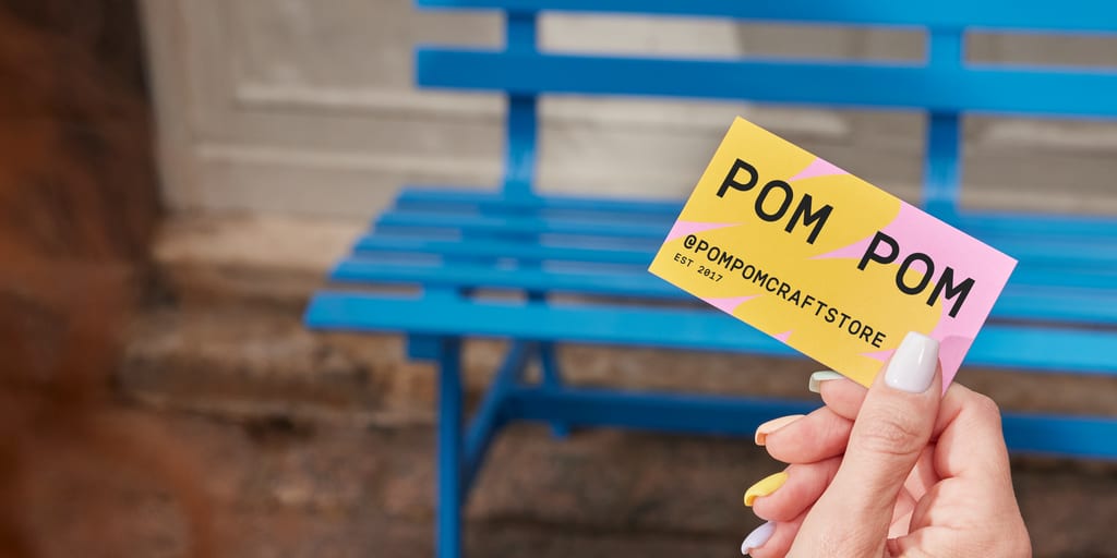 Female hand holding a colorful business card with company name and social contact – how to make business cards on Word.