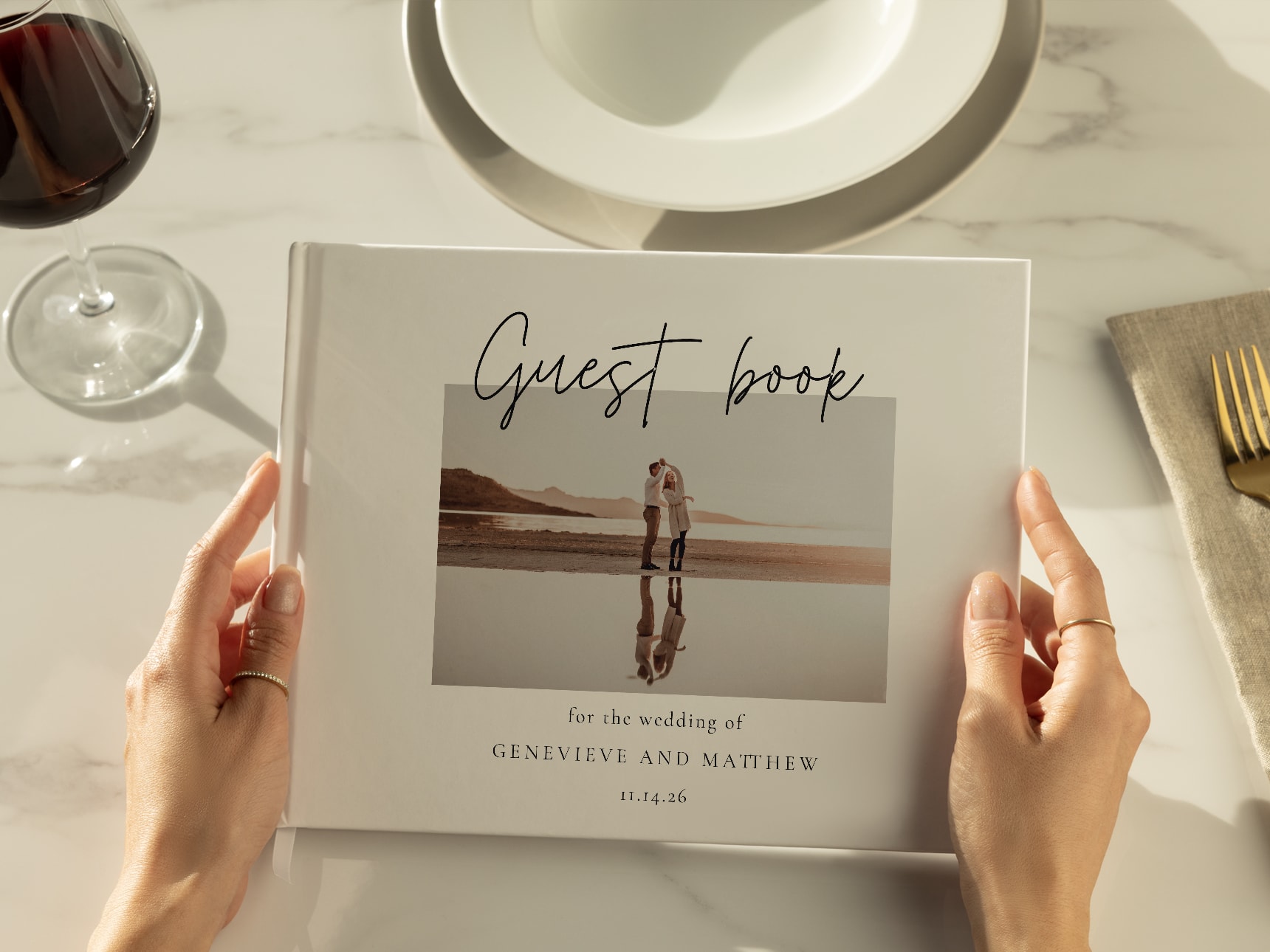 Close-up of a personalized wedding guest book held by a guest, featuring a photo of the couple and elegant script text.