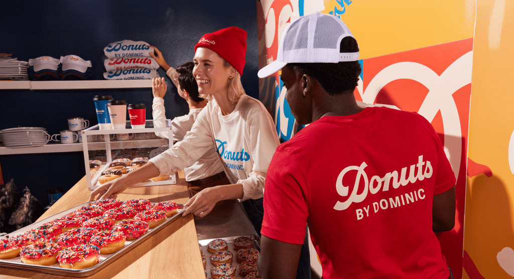 A donut shop employee wearing a branded cap as work uniform