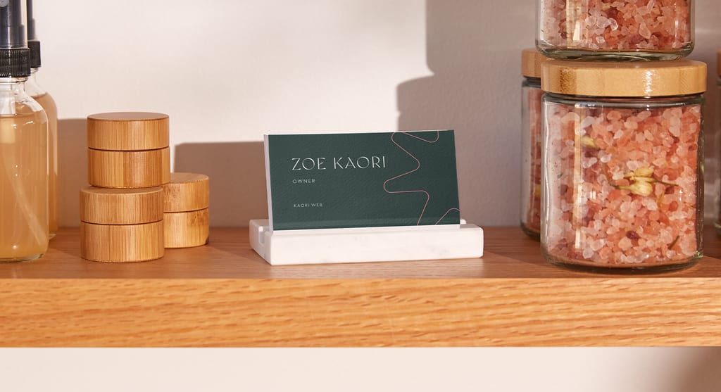 Business cards sitting in a wooden holder on a store shelf.