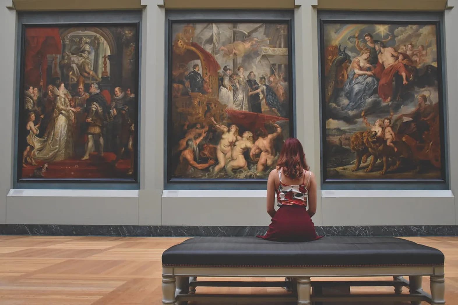 Women sitting in front of paintings at an art museum.