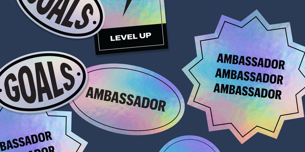 Assorted holographic stickers in different shapes including oval and starburst with ambassador and goals text