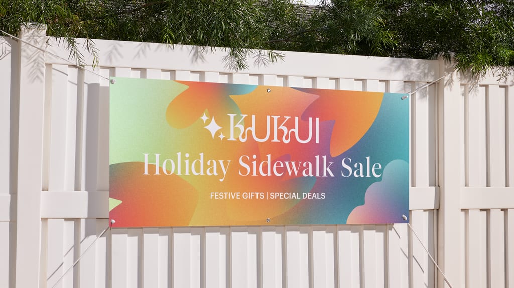 Colorful promotional banner hanging on a white fence, showcasing festive branding and message – example of banner materials in use.