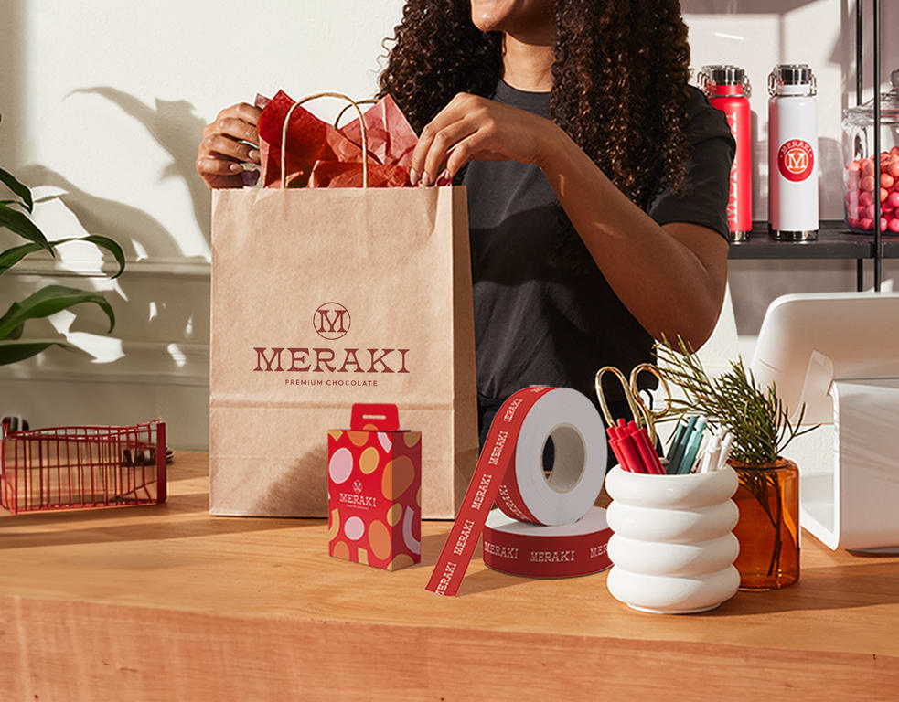 Person doing finishing touches to their holiday packaging with branded stationary next to them.
