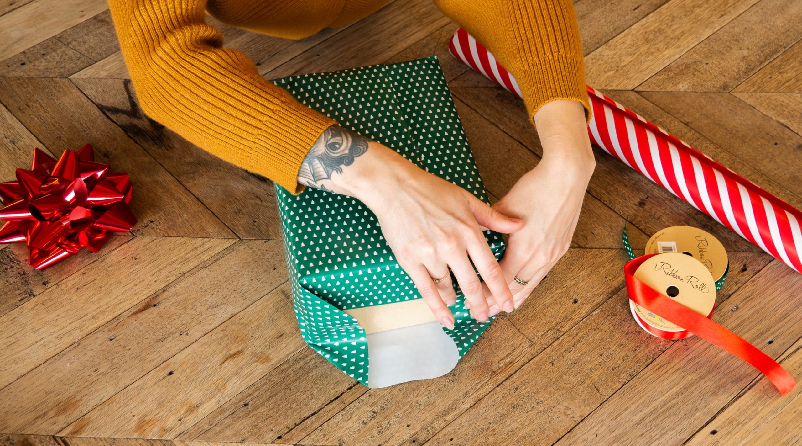 Eine Person faltet Laschen ins Geschenkpapier