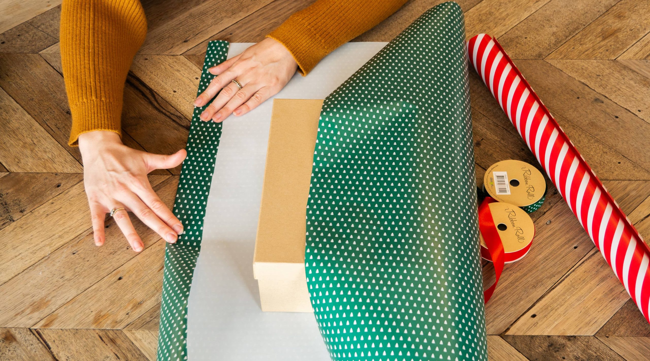 EIne Person faltet vorher zugeschnittenes Geschenkpapier