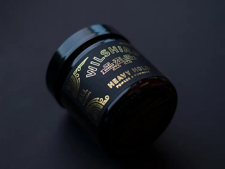 A container of hair pomade using the color trends 2026 Clubroom Contrast black and gold