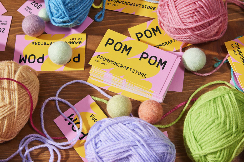 Bright artist business card in yellow and pink with playful yarn imagery, demonstrating how bold colors and textures can showcase creativity and personality.