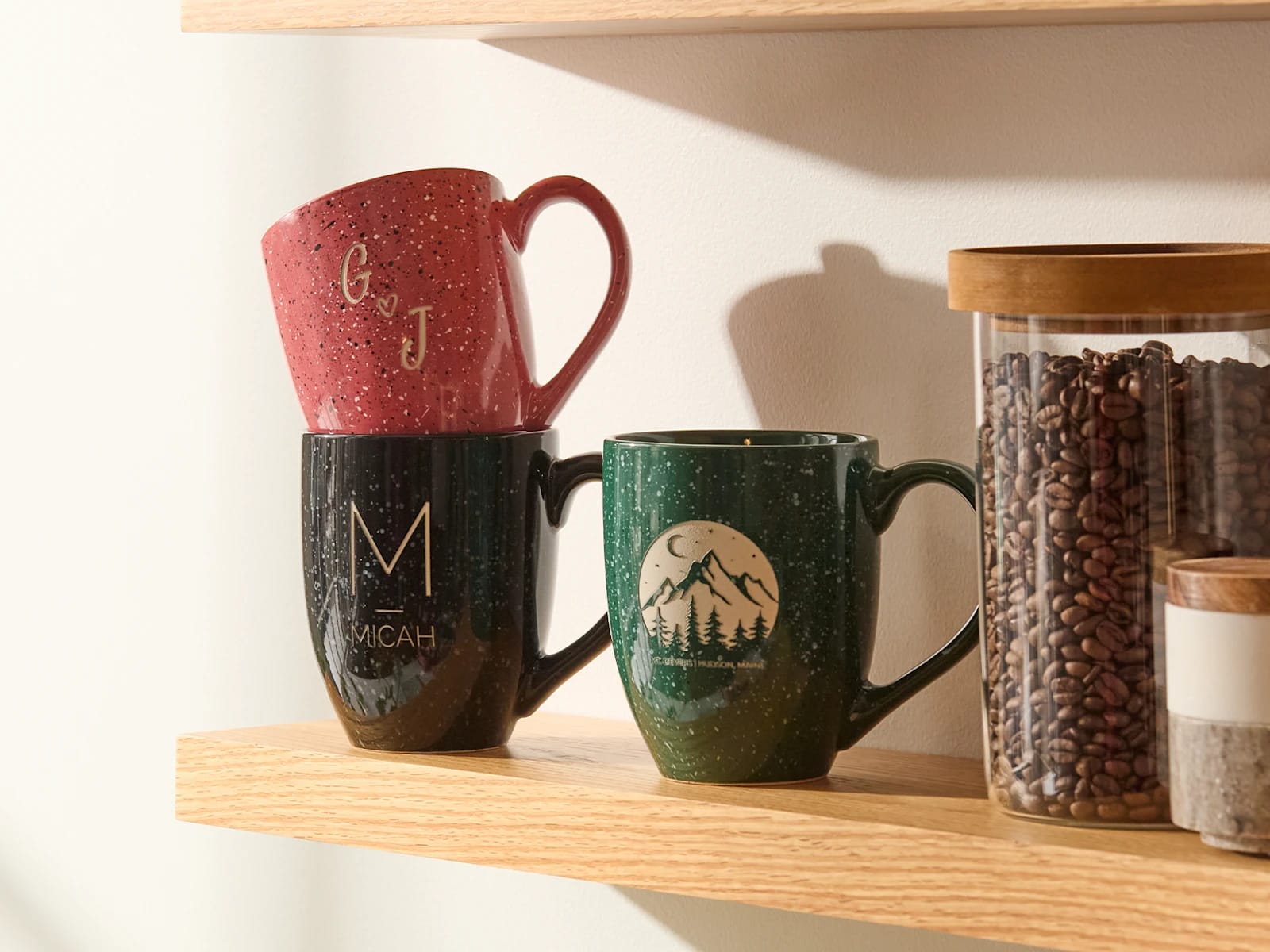 Customized mugs in black, red and green, sitting on a shelf