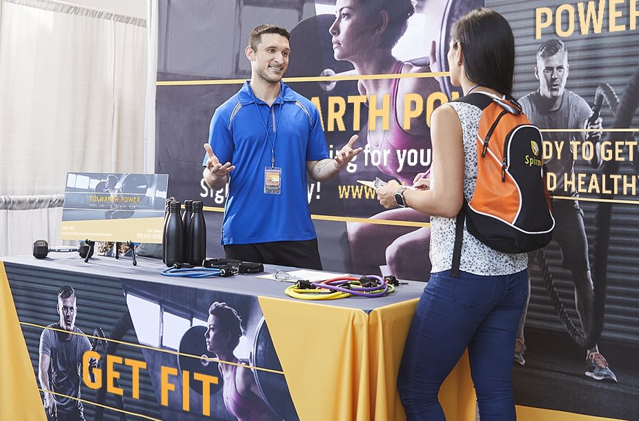 A man and woman talking at a gym’s stand at a business conference
