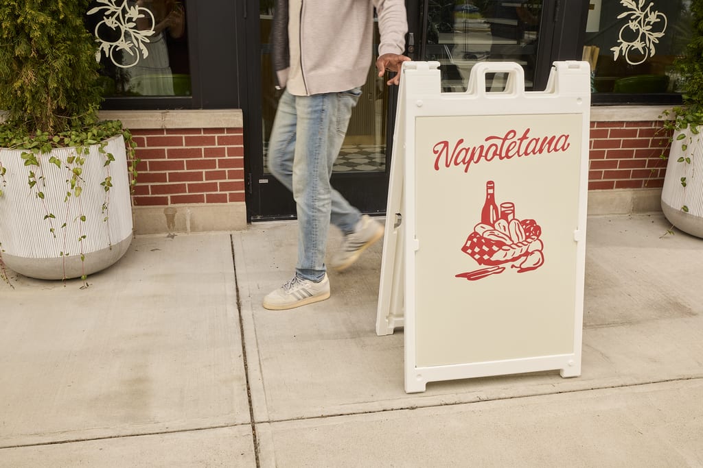 White and red sandwich board signage in the street advertising an Italian restaurant