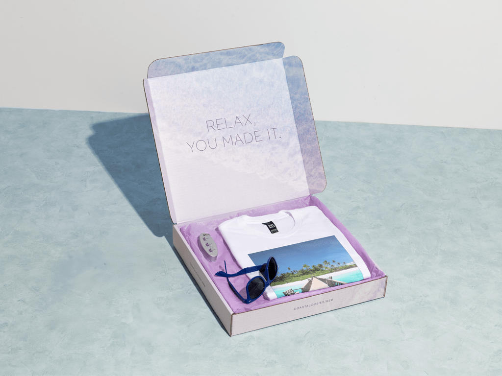 A branded mailer box containing sunglasses and a t-shirt