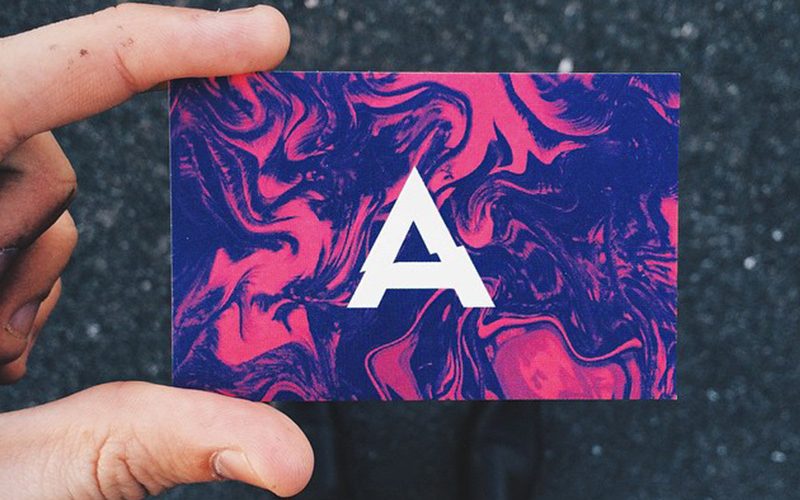 pink and purple tye-dye inspired business card with a large, centralized white letter A