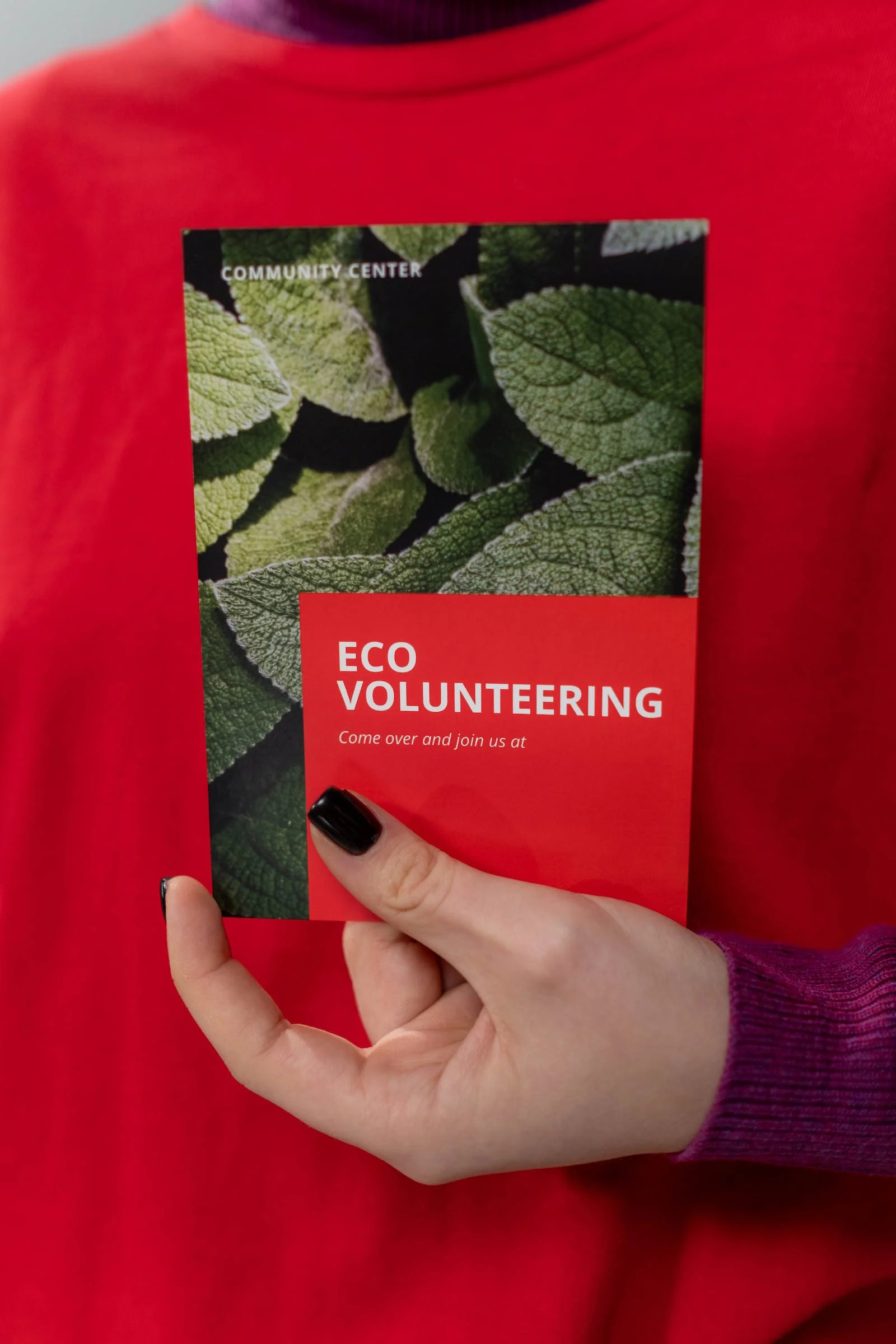 A person holding a red eco-volunteering brochure
