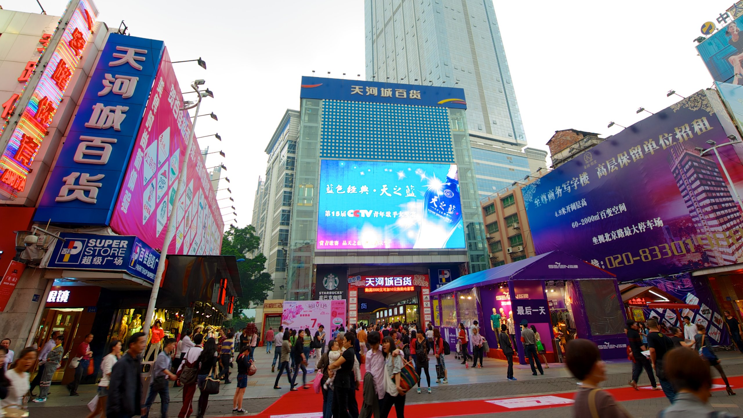A busy street with tall buildings and colorful digital billboards