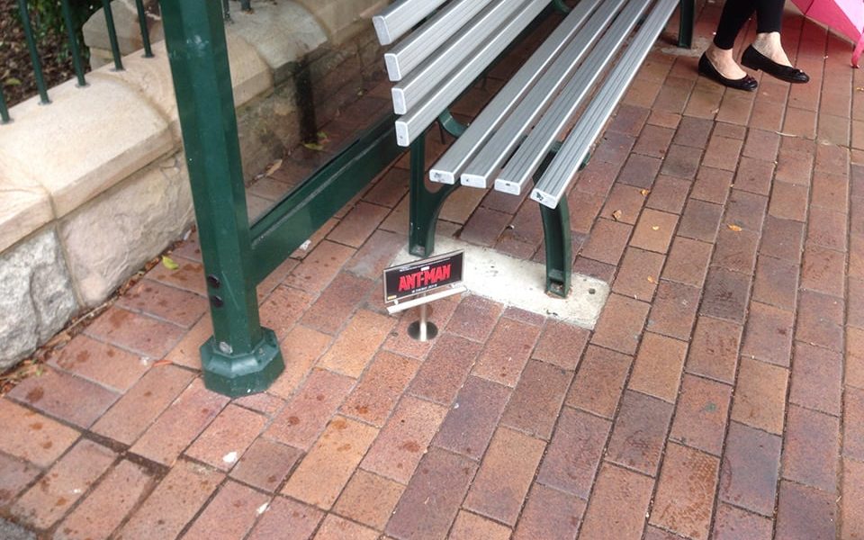A small billboard advertising the Ant-Man movie next to a bench