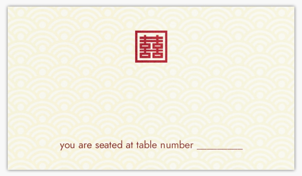 place card featuring a tan fan-like design background and red monogram