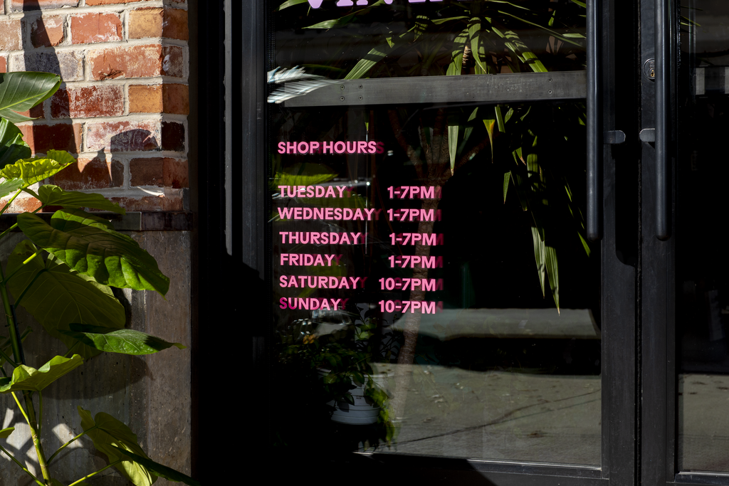 Pink window decal with shop hours.
