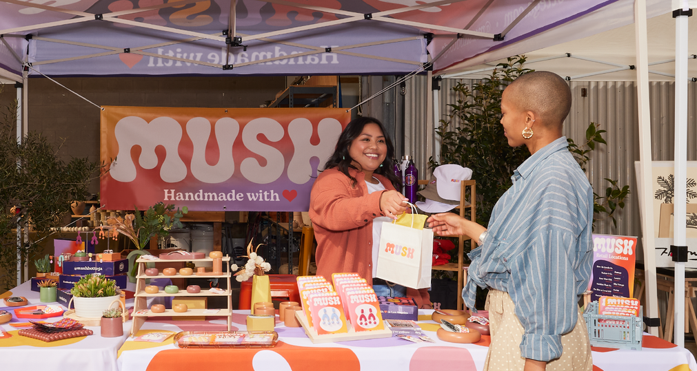 Small business owner handing a bag to a customer at a trade show