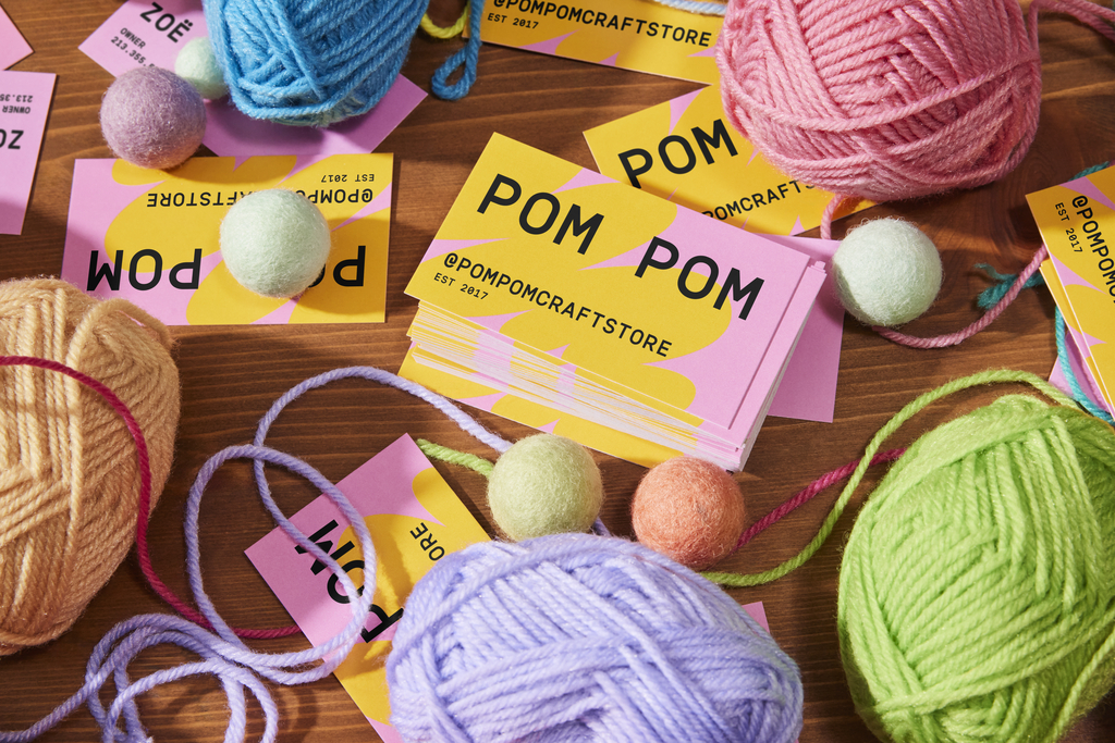 Bright artist business card in yellow and pink with playful yarn imagery, demonstrating how bold colors and textures can showcase creativity and personality.