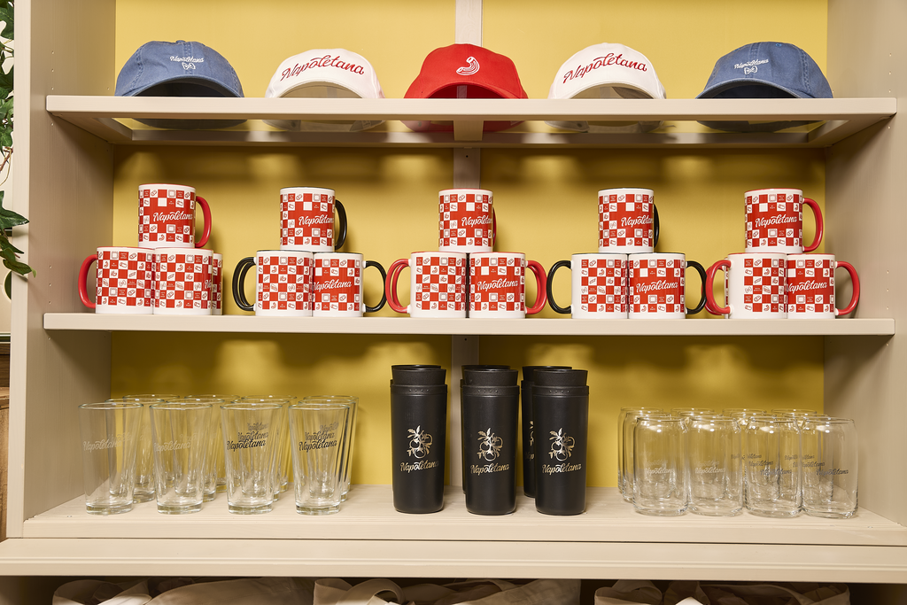 Wooden shelves with branded glasses, water bottles, coffee mugs, and caps