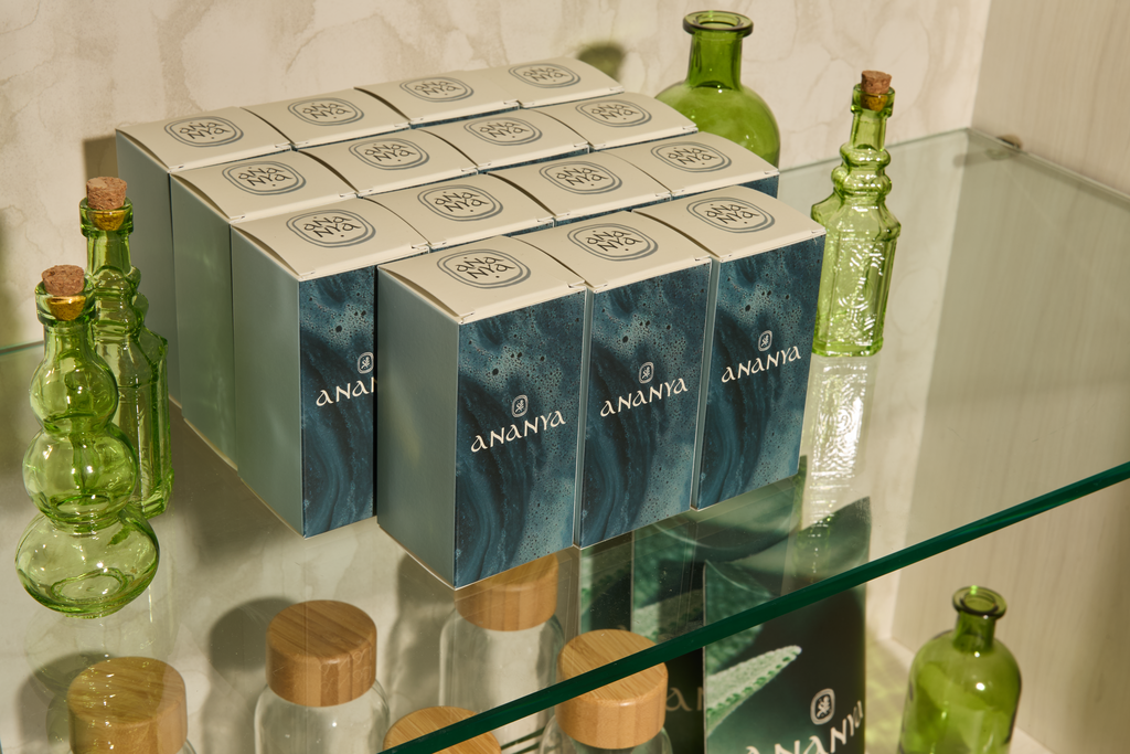 Selection of identical rectangular product packages on shelf with abstract design and logo on front panels and black and white logo on top panel