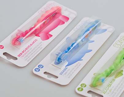 Three colourful children’s toothbrushes in blister pack packaging with display cards on a light grey background.