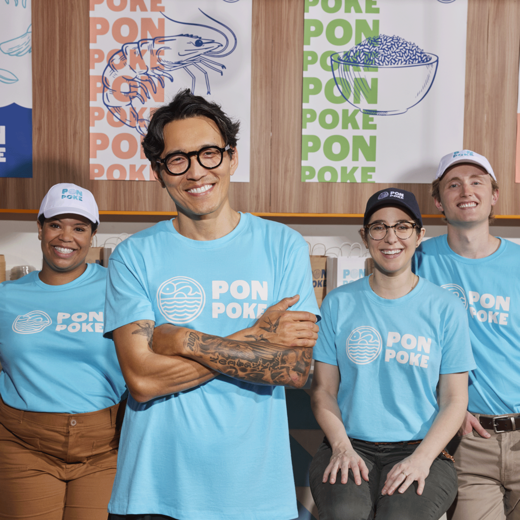 A poke restaurant team wearing blue branded T-shirts with logos on the front