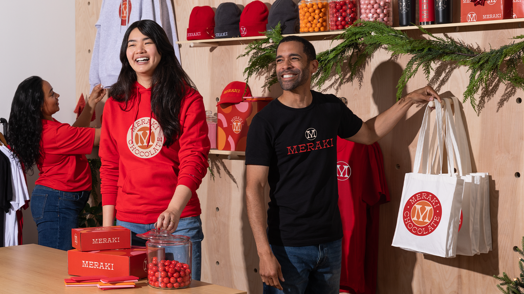Three shop employees wearing branded uniforms with simple logos printed on