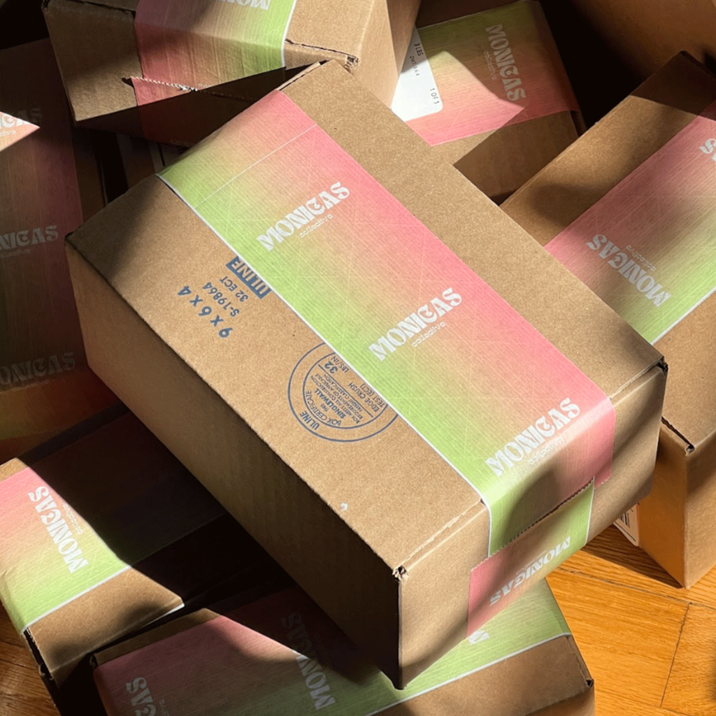 A cardboard shipping box with branded green and pink tape