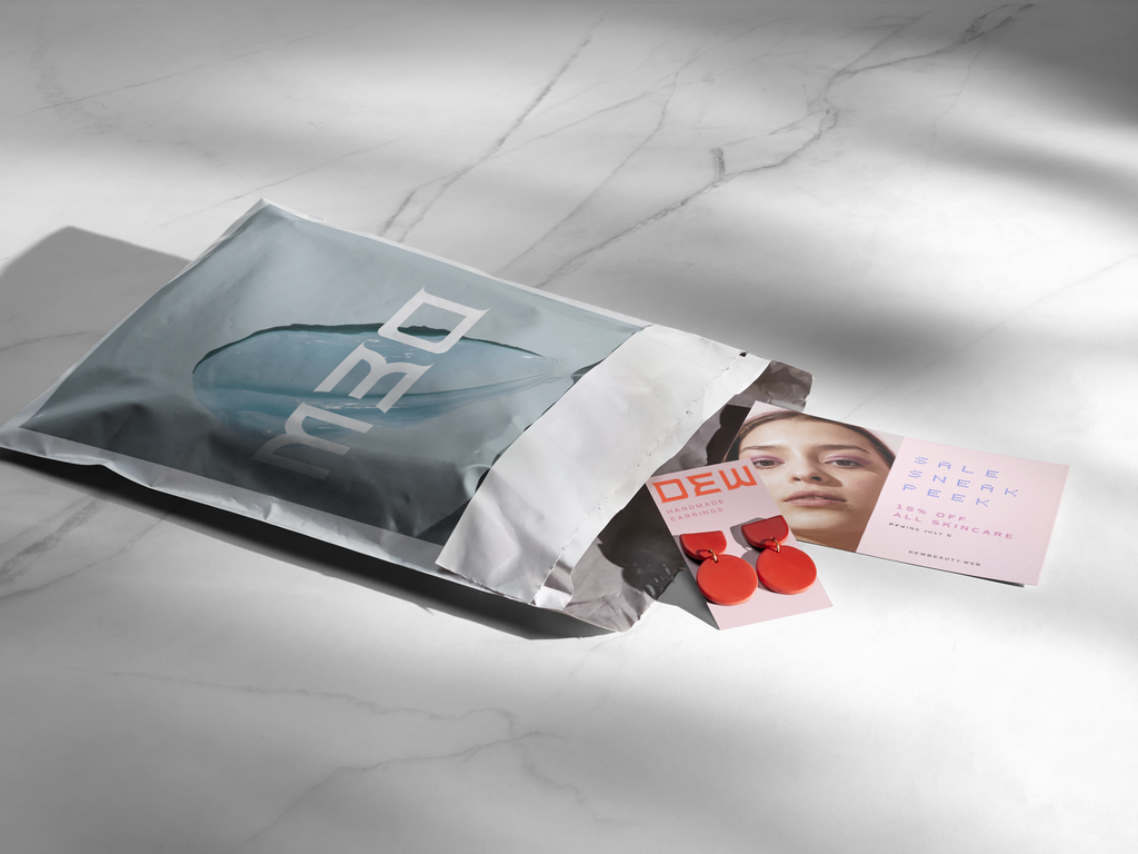 Printed postcard and earrings inside a branded poly mailer