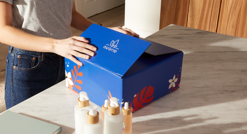 Employee closing a blue branded shipping containing skincare bottles