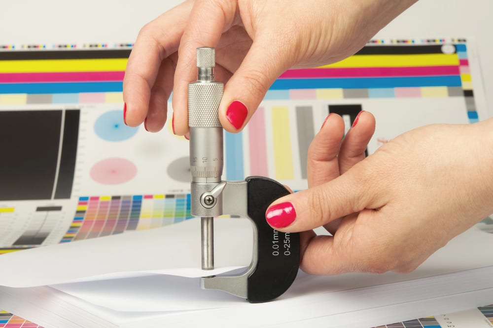 Photo of a paper specialist measuring paper thickness with a caliper