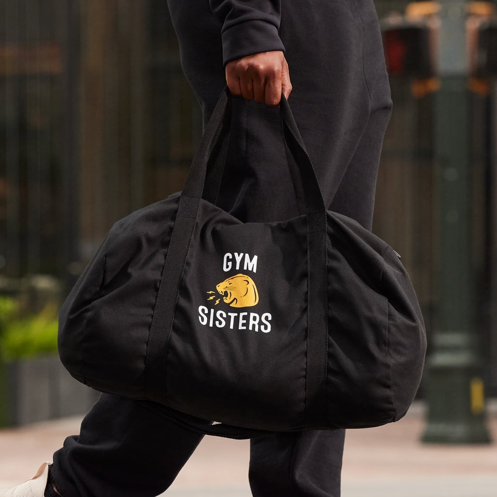 Person carrying black branded gym duffel bag