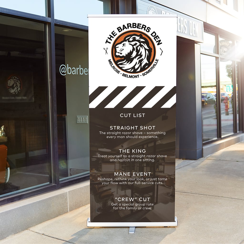 Retractable banner outside of barber shop with a haircut service list