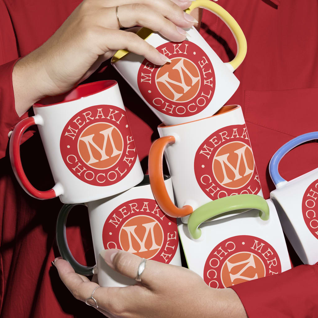 Woman holds several colorful branded mugs each with a handle in a different color.