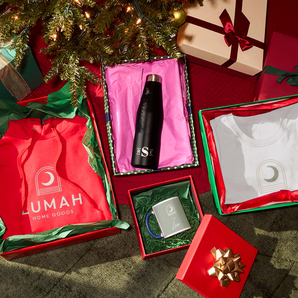 Boxed branded holiday gifts with colorful tissue paper under a tree.