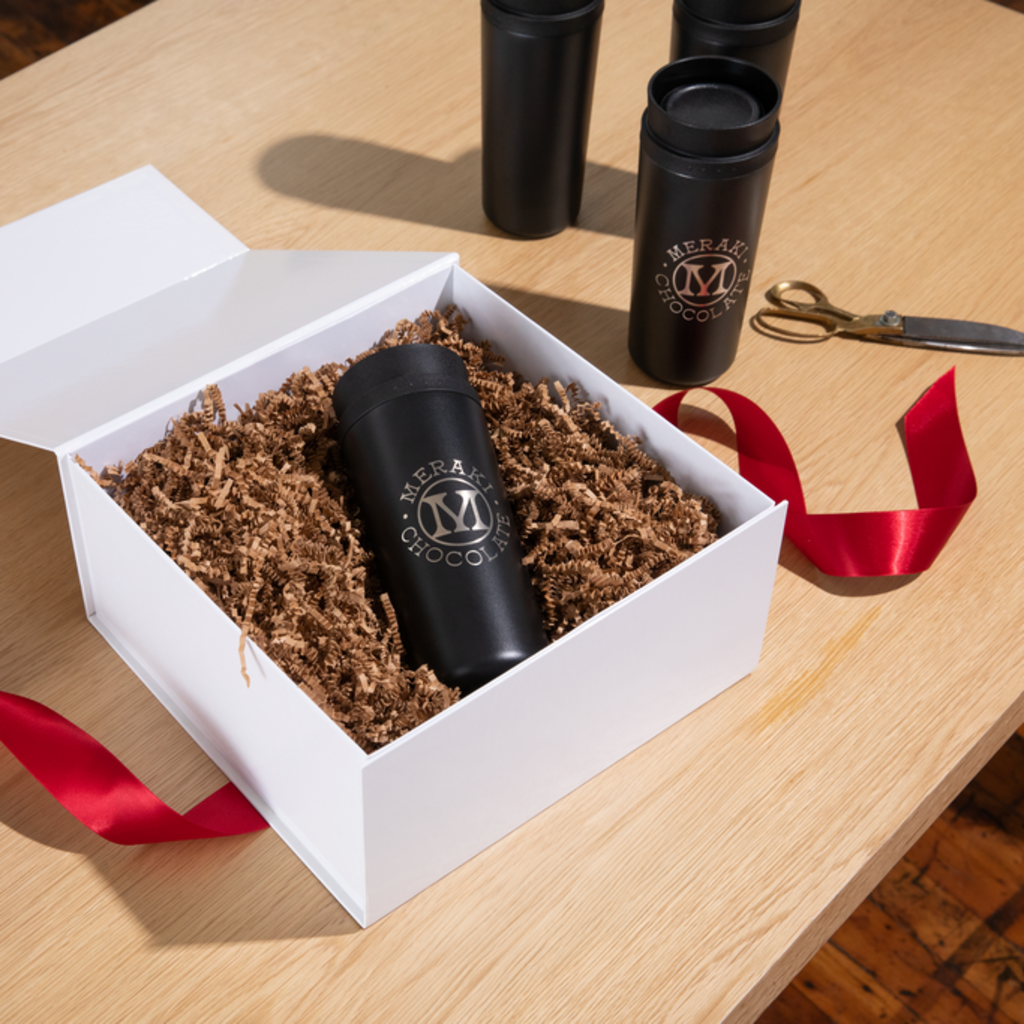 Personalized holiday gift basket with a black branded drinks bottle in a white box with shredded filler and a red ribbon