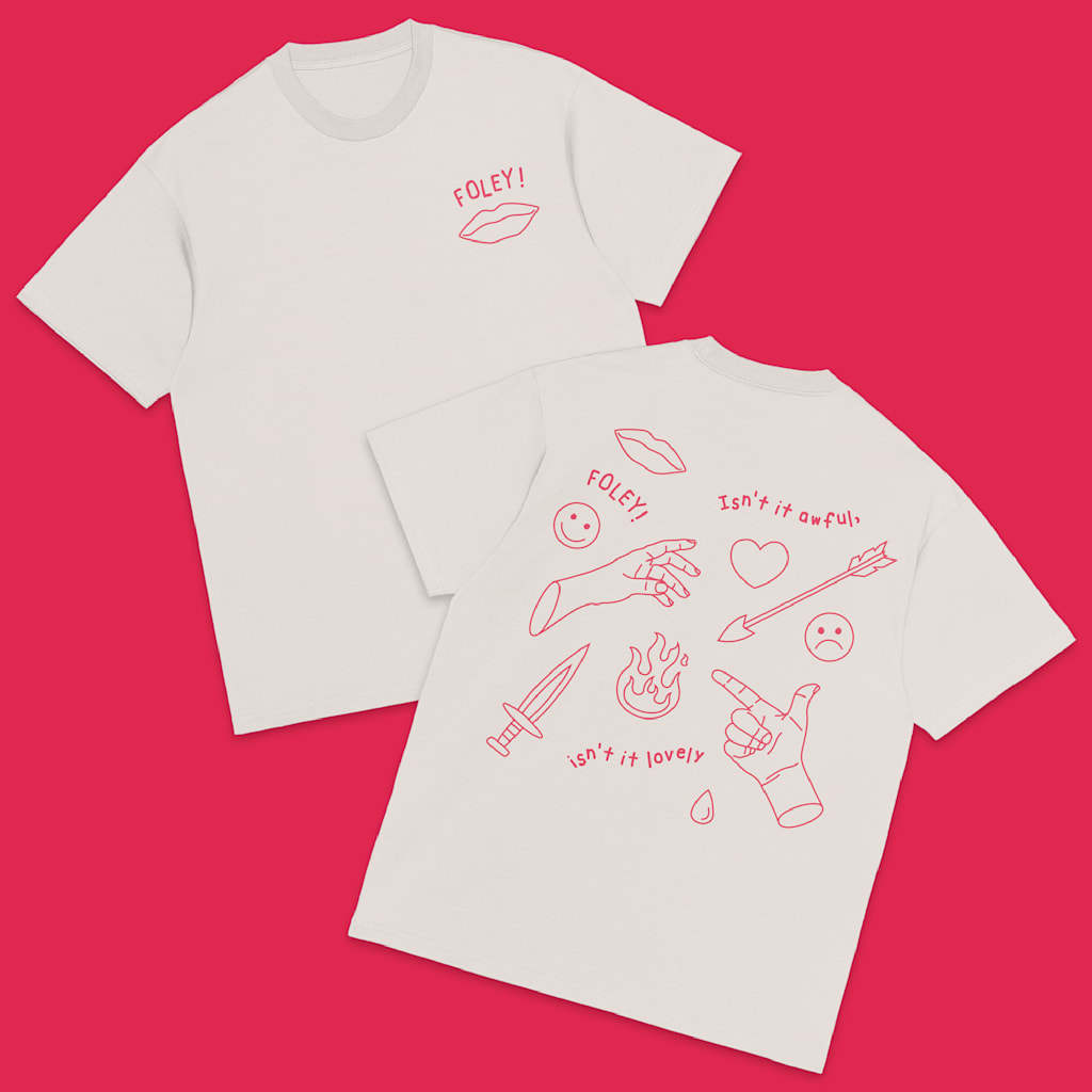 White T-shirt with pink hand drawn style graphics of lips, heart, arrow, hands, dagger and flame with font &ldquo;FOLEY!&rdquo;