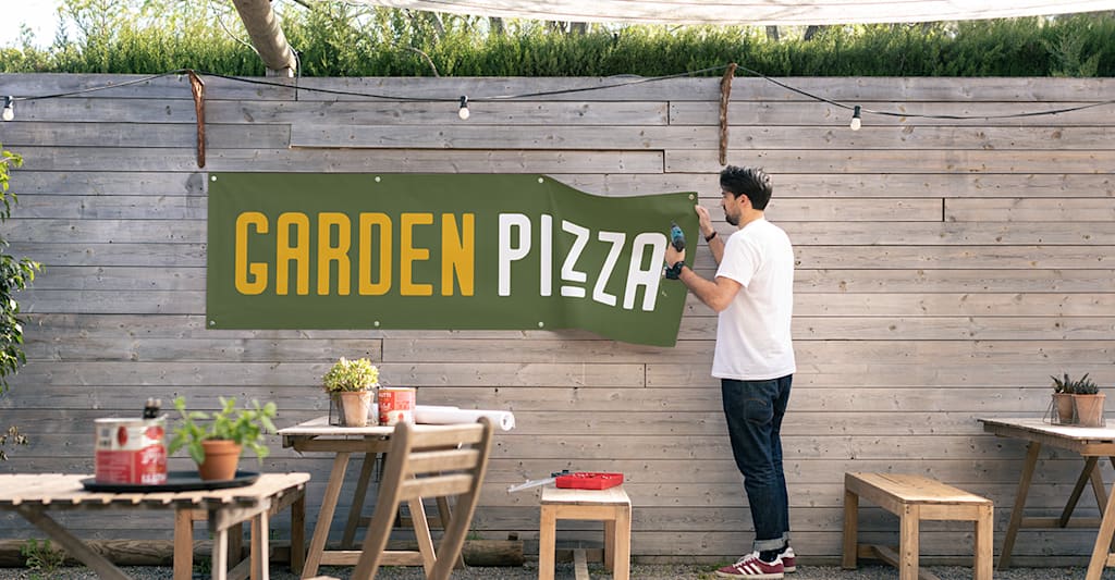 A mesh banner promoting a pizzeria, displayed in their dining area.