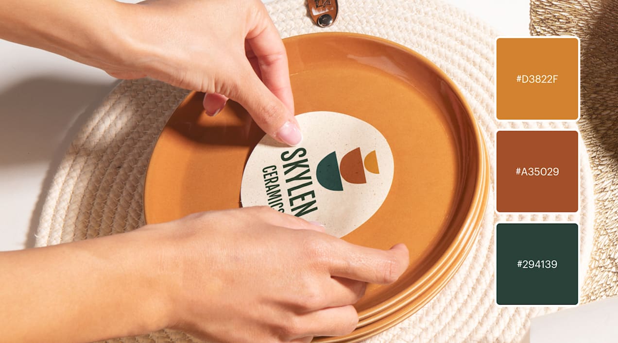 Woman places sticker featuring minimalistic ceramics logo of stacked bowls in earthy shades terra cotta, ocean blue and beige.