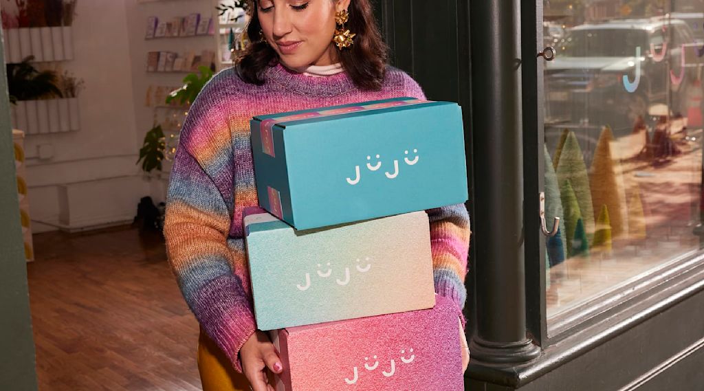 A small business owner carries branded packaging boxes