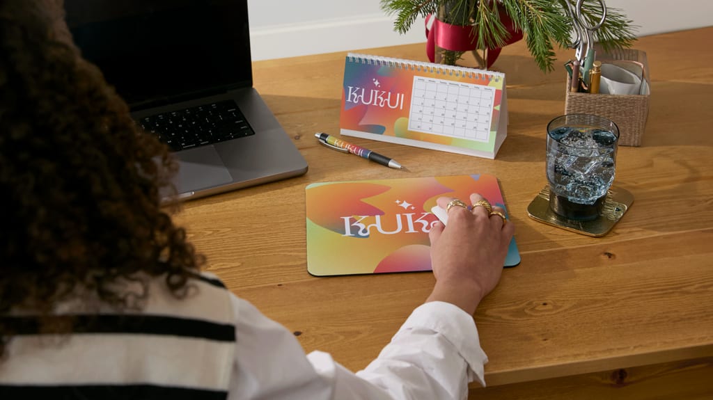 Une employée à son bureau avec un calendrier et un tapis de souris personnalisés