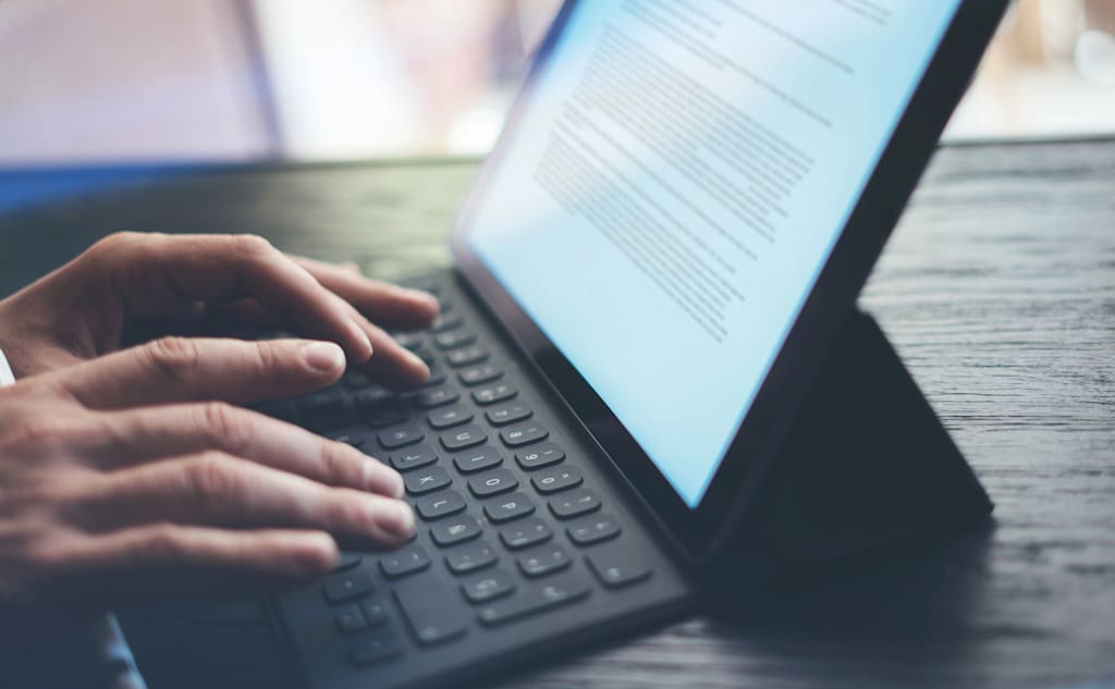 Hands typing on a tablet keyboard.