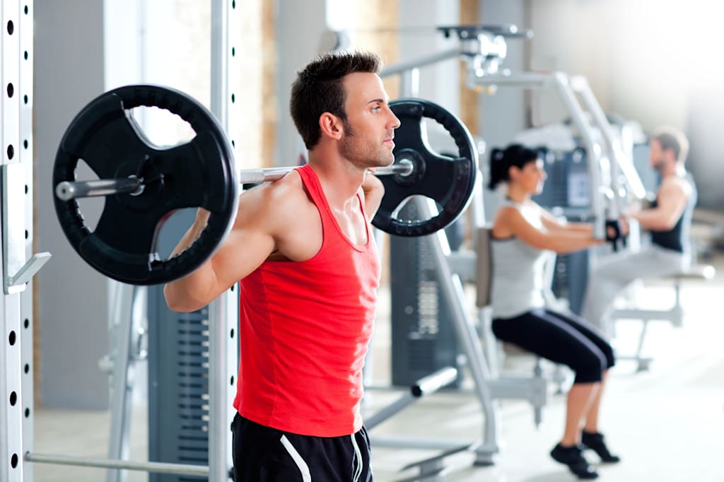 Gym goers lifting weights and using gym machinery.