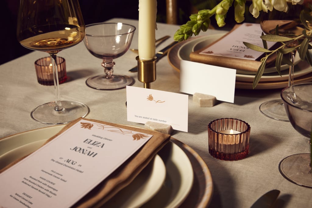 Table cards and menus surrounded by glassware and crockery on a wedding dinner table