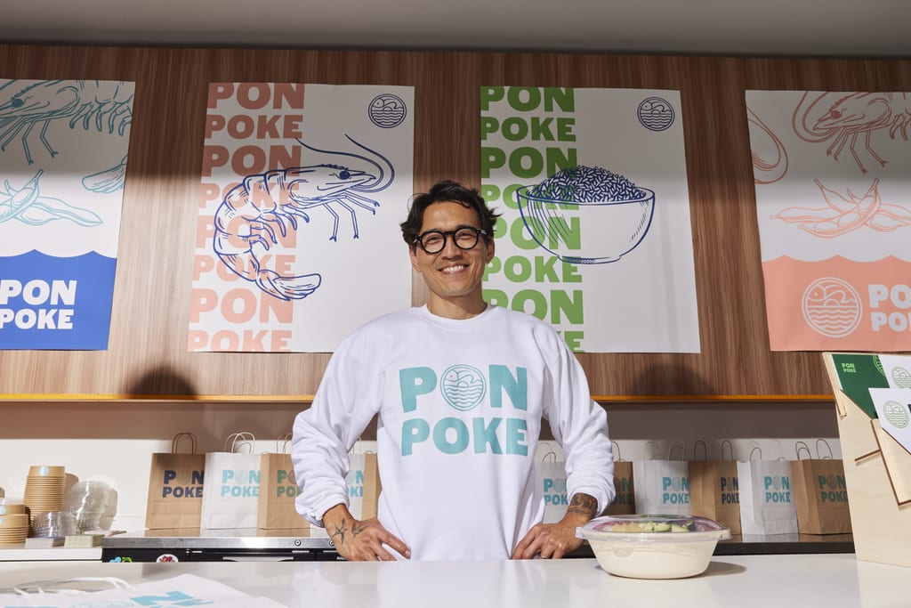 A poke shop business owner wearing a branded sweater.
