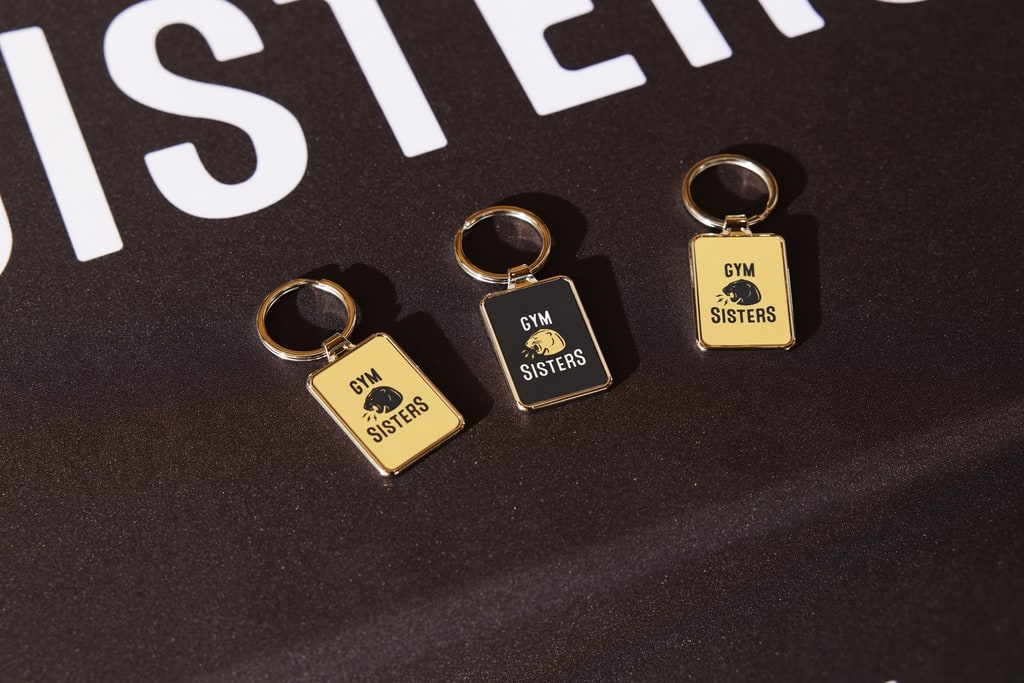 Three branded keychains with the brand logo printed onto the plastic and metallic surface of the merch product