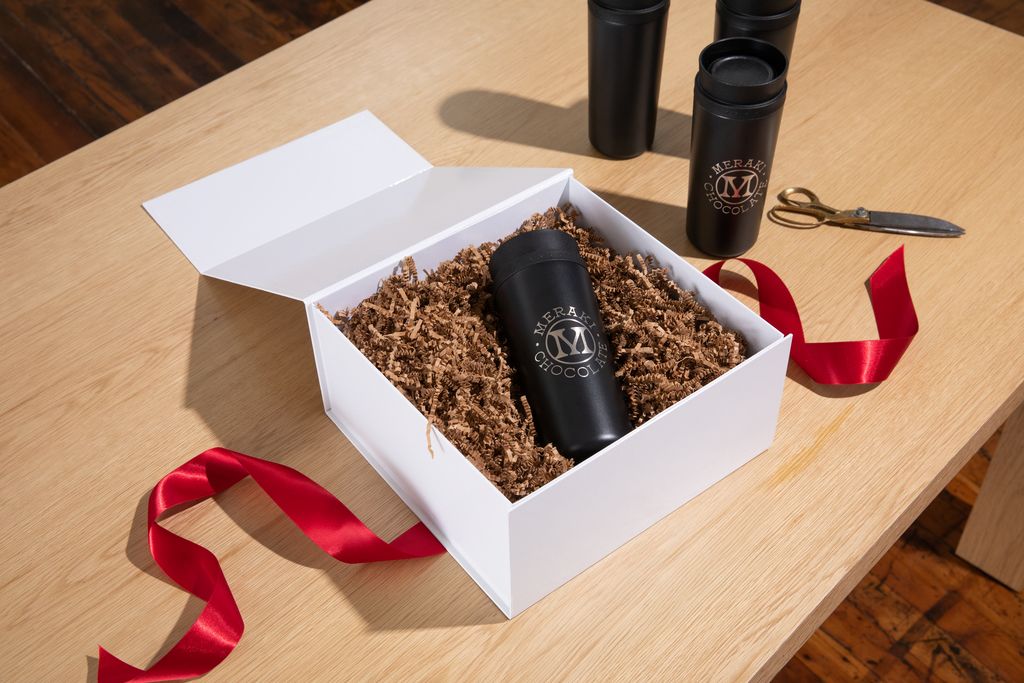 Black branded tumbler with logotype featured in an open white gift box with red ribbon