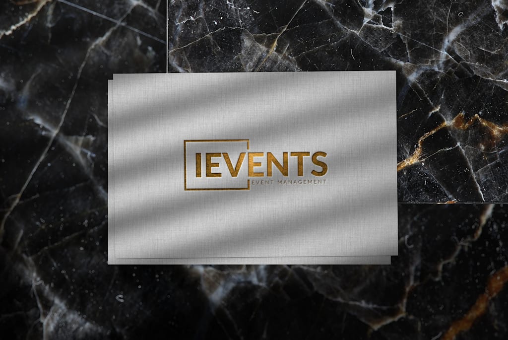 A stone colored business card with gold embossed text, on a black marble background
